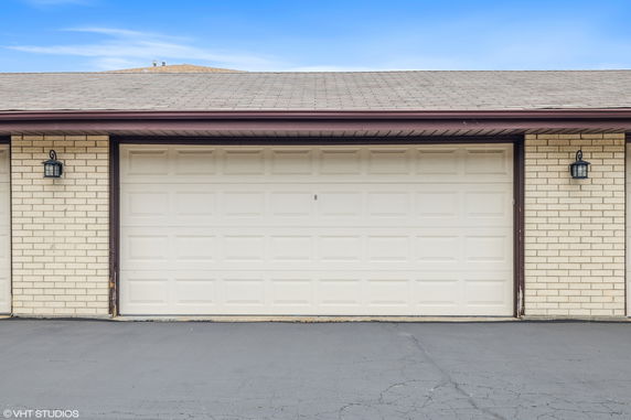 Front view of a garage with a single large white door and brick walls.