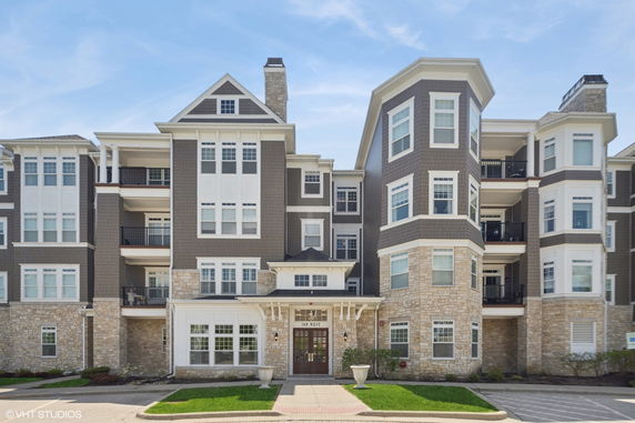 Front view of a multi-story apartment building with a stone facade and multiple balconies.