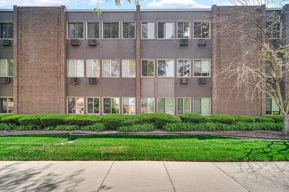 Front view of a three-story building with brick and panel facade.