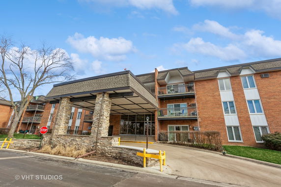 Front view of a multi-story brick building with balconies and a covered entrance.
