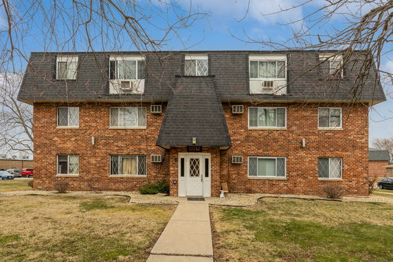 Front view of a brick apartment building with multiple windows and a central entrance.