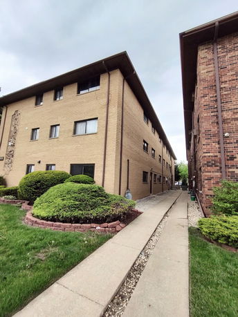 Front view of a three-story apartment building with tan brick exterior.