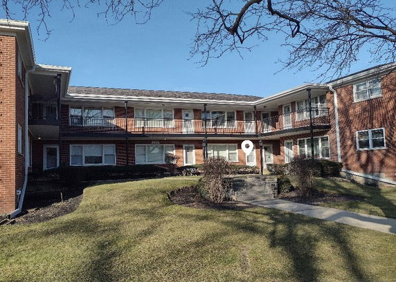 Front view of a two-story residential building with a brick facade and multiple balconies.