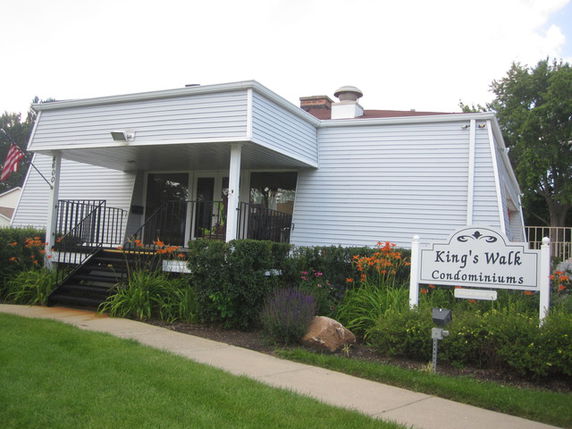 Front view of a single-story condominium building with a small porch and entrance stairs.