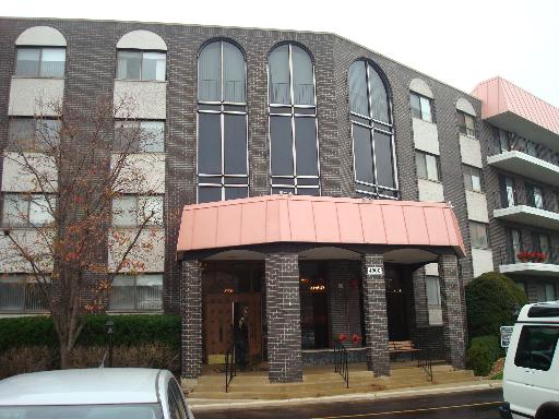 Front view of a multi-story building with large arched windows and a covered entrance.