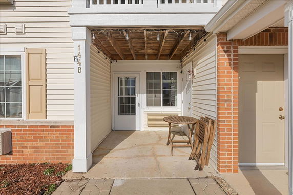 Front view of a house with a small patio area and white siding.