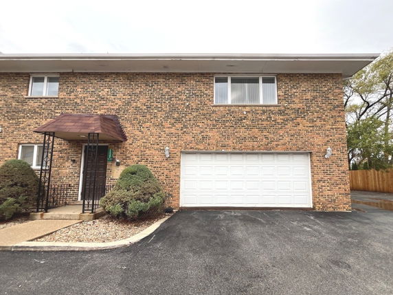 Front view of a two-story brick house with a single garage.