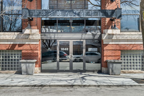 Front view of a building entrance with brick facade and glass doors.