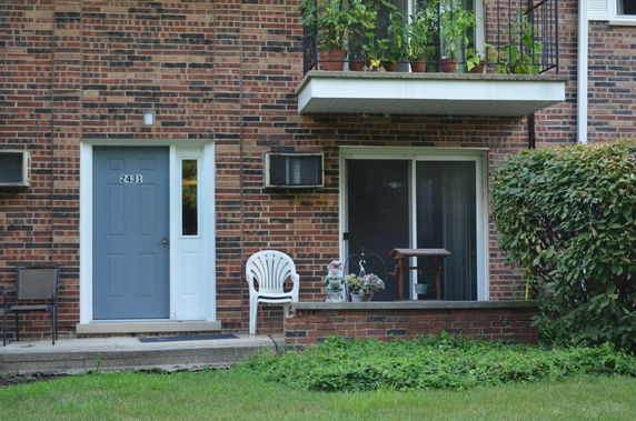 Front view of a brick residential building with a blue door and a small balcony.