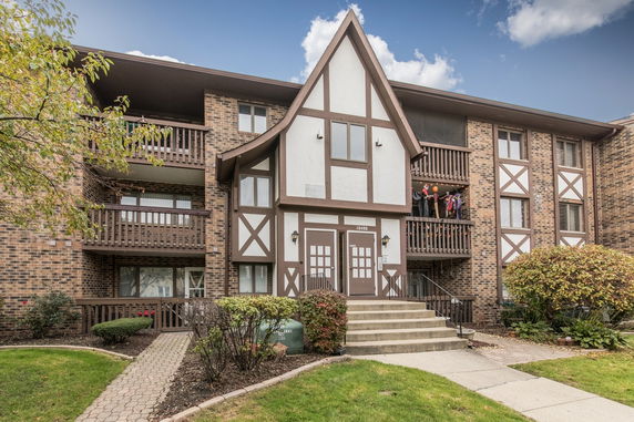 Front view of a three-story building with brick facade and wooden balconies.