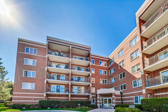 Front view of a multi-story brick apartment building with balconies.