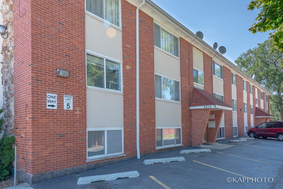 Front view of a multi-story brick building with parking spaces.