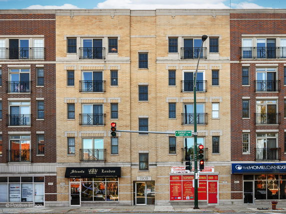 Front view of a multi-story brick building with commercial spaces on the ground floor.