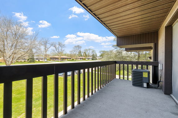 View from a balcony with railing overlooking residential area and trees.