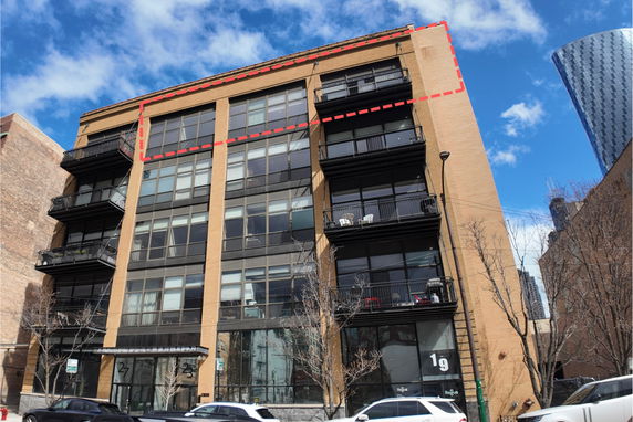 Front view of a multi-story building with large windows and balconies.