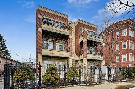 Front view of a multi-story brick building with balconies and iron fencing.