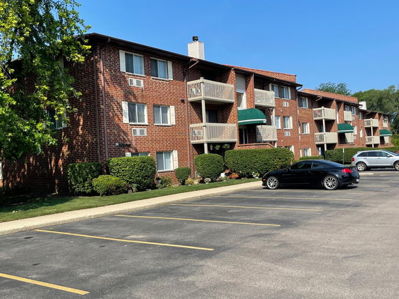 Front view of a three-story brick apartment building with balconies.