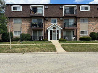 Front view of a multi-story brick building with balconies and a central entrance.