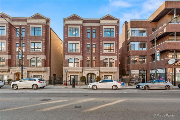 Front view of a multi-story brick building with large windows.
