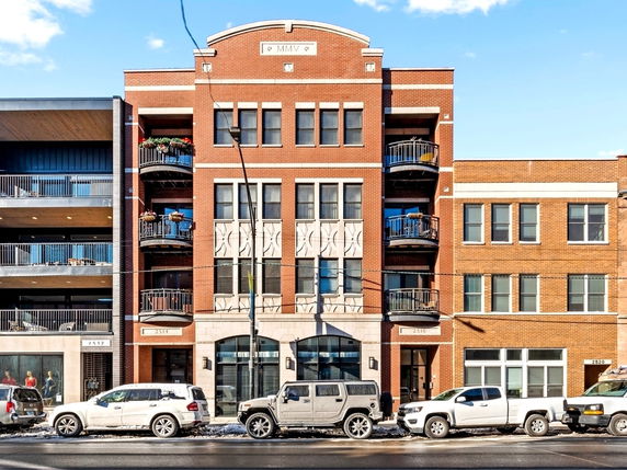 Front view of a multi-story brick building with balconies and arched windows.