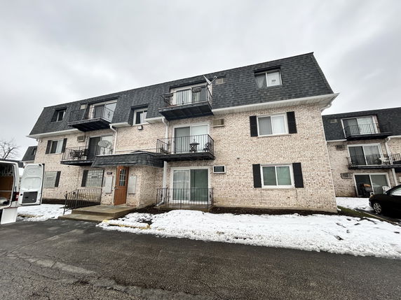 Front view of a three-story apartment building with balconies and a brick exterior.