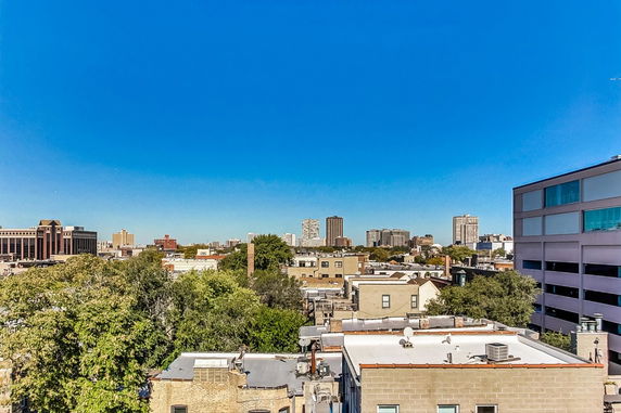 Panoramic view of city buildings and skyline under a clear blue sky.