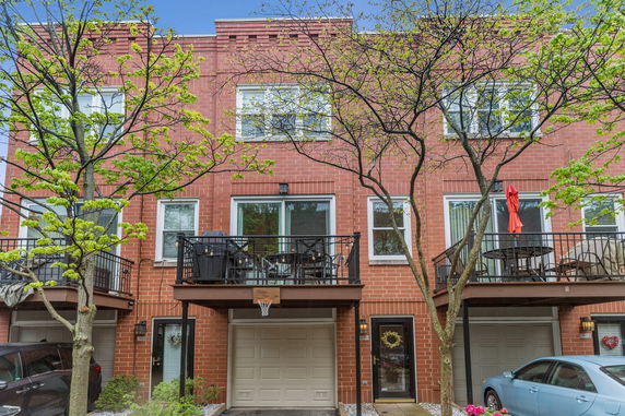 Front view of a multi-story brick townhouse with balconies and garages.