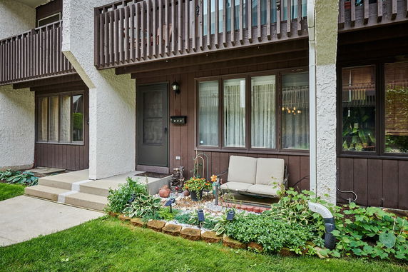 Front view of a two-story house with a balcony and garden area.