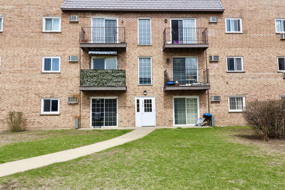 Front view of a multi-story brick apartment building with balconies.
