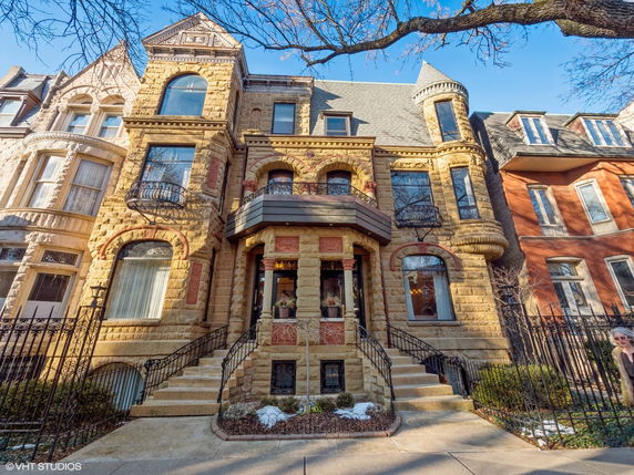 Front view of a multi-story historic building with arched windows and stone facade.