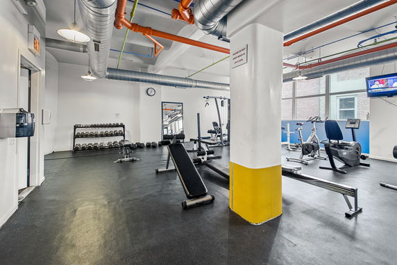 Interior view of a gym with exercise equipment and weights.
