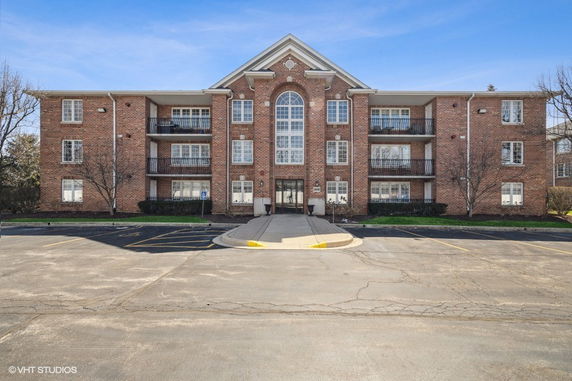 Front view of a three-story brick apartment building with balconies.
