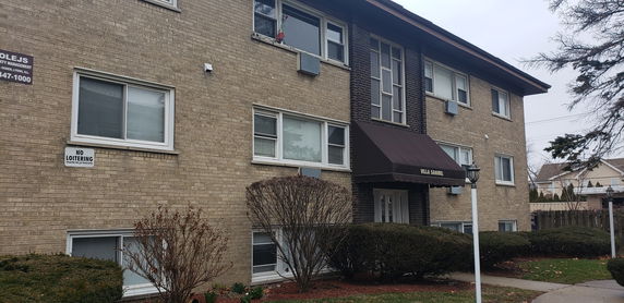 Front view of a multi-story brick apartment building with several windows.