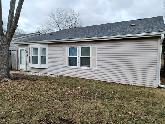 Side view of a single-story house with a gray roof and light-colored siding.