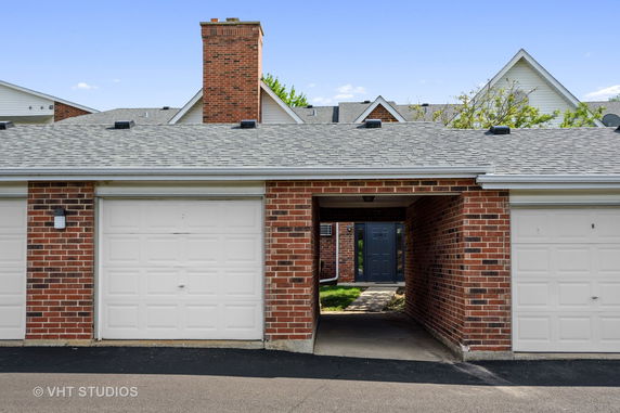 Front view of a brick house with a garage and a pathway.