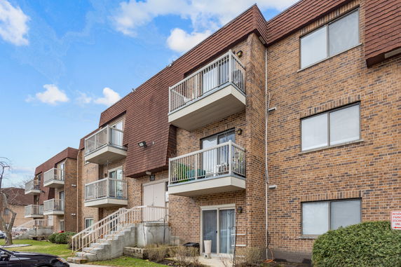 Front view of a multi-story brick apartment building with balconies.