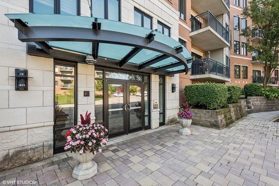 Front view of a building entrance with glass canopy and potted plants.