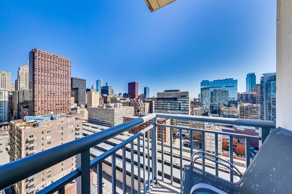 Wide-angle view from a balcony overlooking a city skyline with tall buildings.