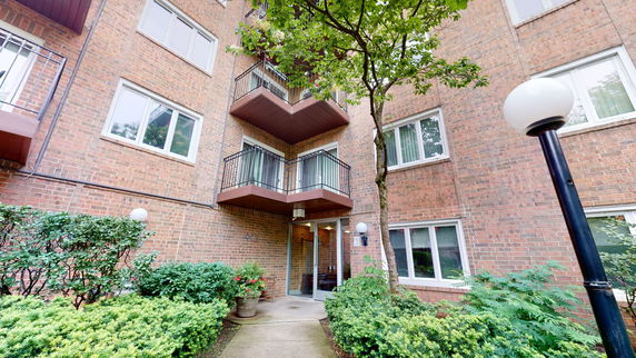Front view of a multi-story brick building with balconies and a main entrance.