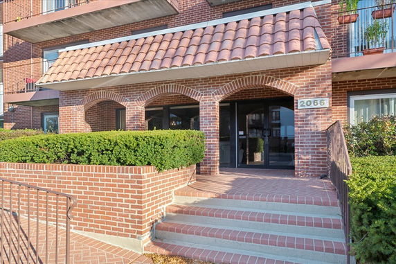 Front view of a brick building with arched entrance and tiled roof.
