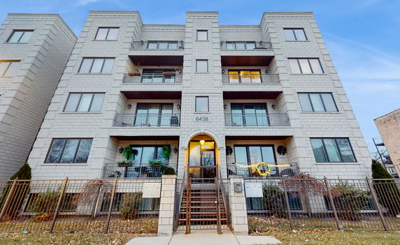 Front view of a four-story apartment building with balconies.