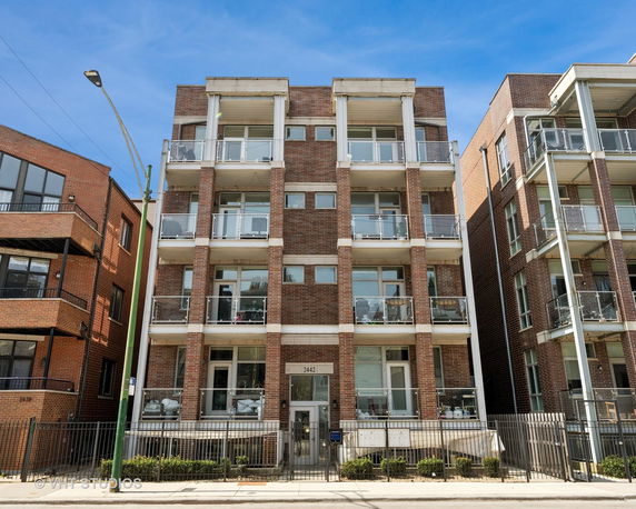 Front view of a multi-story brick apartment building with balconies.