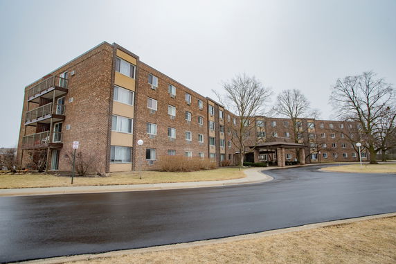 Front view of a four-story brick apartment building with balconies.