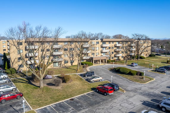 Front view of a multi-story apartment building with balconies and parking area.