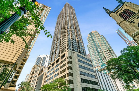 Front view of a tall skyscraper with multiple windows and adjacent high-rise buildings.