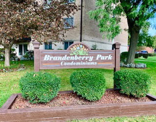 Front view of a multi-story condominium building with a sign in front.