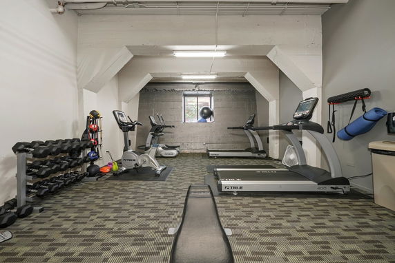 Indoor gym area with exercise equipment including treadmills and dumbbells.