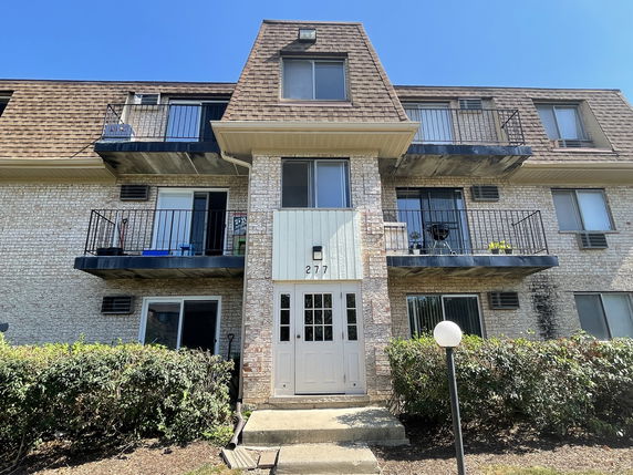 Front view of a multi-story apartment building with balconies.