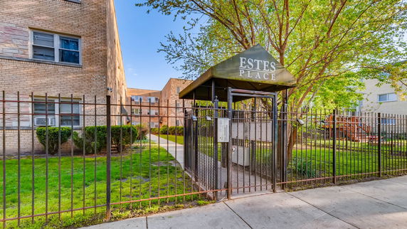 Front view of a multi-story brick building with a gated entrance.