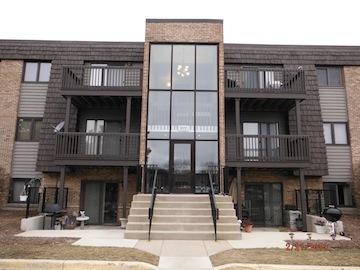 Front view of a multi-story apartment building with balconies and a central staircase.